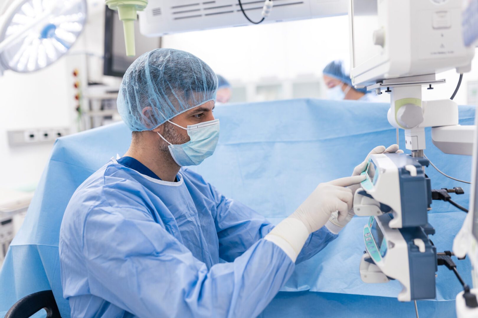 Doctor in blue scrubs operating machinery.