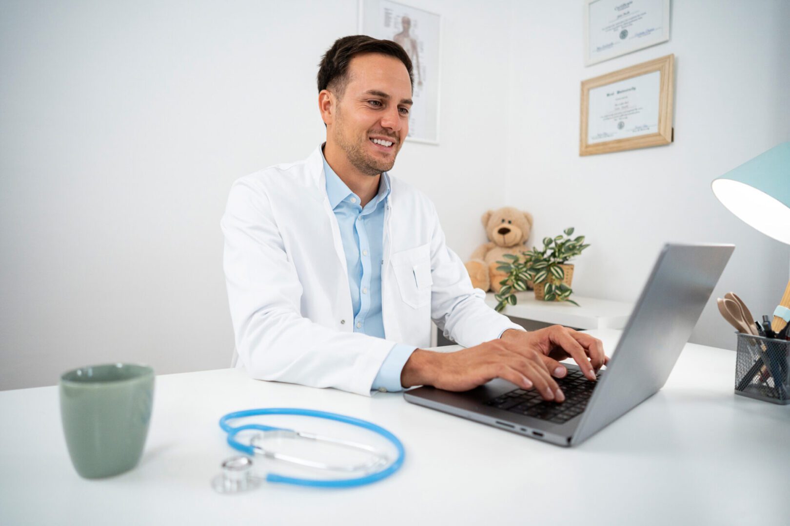 Smiling doctor typing on a laptop.